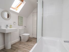 A bathroom with a tub, sink, toilet, and mirror at Coastal Cottage The Bay near Filey