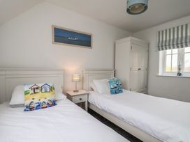 A bedroom with two beds and a wardrobe at Coastal Cottage The Bay near Filey