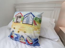 A pillow featuring beach huts and boats on a bed at Coastal Cottage The Bay near Filey