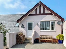 Exterior of a house with a white door bench and potted plant at Monkbarns in Brixham