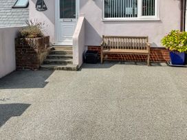 The front entrance of a house with concrete steps a wooden bench a window a planter with plants and a door at Monkbarns in Brixham