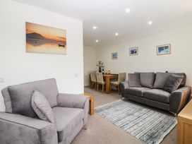 A living room with two gray sofas a patterned rug a wooden dining table with chairs and landscape pictures on the walls at Monkbarns in Brixham