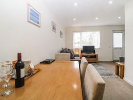 A dining table with wine and glasses in a living room with a sofa and a television at Monkbarns in Brixham