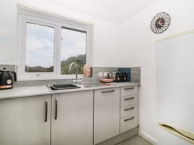 A kitchen with a window above a sink a kettle a toaster and a clock on the wall at Monkbarns in Brixham