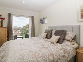 A bedroom with a bed and pillows next to a window with curtains and a wooden dresser at Monkbarns in Brixham