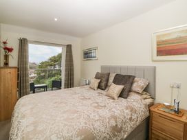 A bedroom with a double bed two bedside tables and a large window with chairs outside at Monkbarns in Brixham