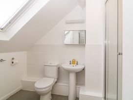 A bathroom with a toilet sink mirror and shower under a sloped ceiling at Monkbarns in Brixham