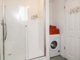 A bathroom with a glass shower enclosure and a washing machine with folded towels on top at Monkbarns in Brixham