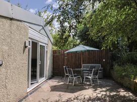 A garden with a table and chairs under an umbrella at Brookfield Lodge in Drimpton