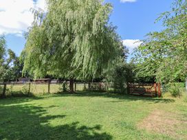 A garden with a tree and a gate at Brookfield Lodge in Drimpton