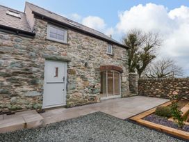 An outdoor view of a stone house with a door and sliding glass door at Storws Tanrallt