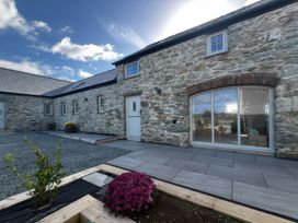An outdoor area with a stone wall and flower bed at Storws Tanrallt Llanfachraeth