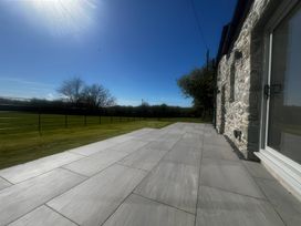 A paved terrace with a grass lawn at Storws Tanrallt in Llanfachraeth