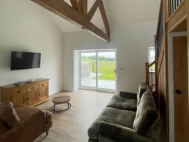A living room with a sofa and television at Storws Tanrallt in Llanfachraeth