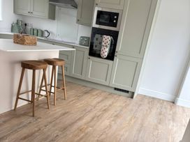 A kitchen with bar stools and cabinets at Storws Tanrallt Llanfachraeth