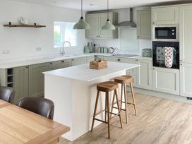 A kitchen with an island and bar stools at Storws Tanrallt in Llanfachraeth