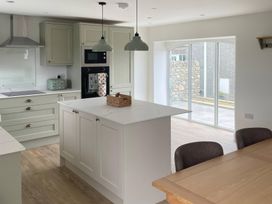 A kitchen with a kitchen island and windows at Storws Tanrallt Llanfachraeth
