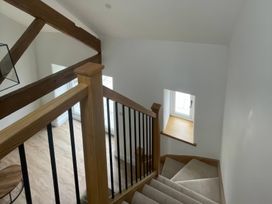 A staircase with wooden beams and a window at Storws Tanrallt Llanfachraeth
