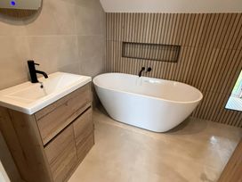 A bathroom featuring a bathtub and a vanity unit at Storws Tanrallt Llanfachraeth