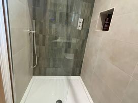 A shower with tiled walls and a bottle in the recess at Storws Tanrallt Llanfachraeth