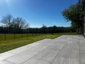 A garden with a patio and grass at Storws Tanrallt in Llanfachraeth
