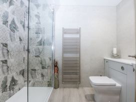 A bathroom with a shower, toilet, towel radiator, and vanity unit at 40 New Row in Pwllheli