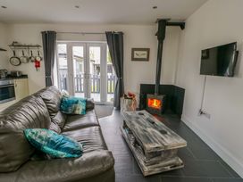 A living room with a sofa and a wood stove at Hafod Wen in Pentraeth