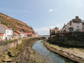 A view of houses alongside a river with cliffs at The Old Cottage in Staithes