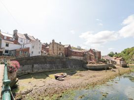 A view of houses along the shore with a boat at The Old Cottage in Staithes