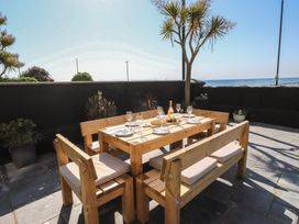 An outdoor dining area with a wooden table and benches at Wavecrest in Pwllheli