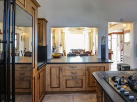 A kitchen with cabinets and a dining area at Wavecrest in Pwllheli