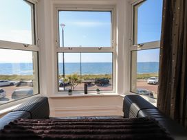 A living room with a view of the sea and parked cars at Wavecrest in Pwllheli