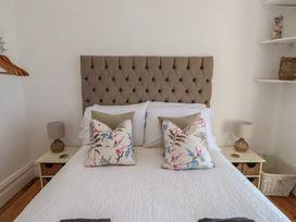 A bedroom with a bed, pillows, lamps, and shelves at Wavecrest in Pwllheli