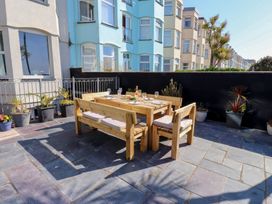 An outdoor dining area with a wooden table and chairs at Wavecrest in Pwllheli