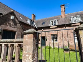 A garden area with stone walls and a gate at Gamekeepers Cottage in Chillingham near Chatton