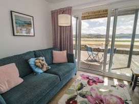 A living room with a sofa and glass doors at Lan y Mor in Porthmadog
