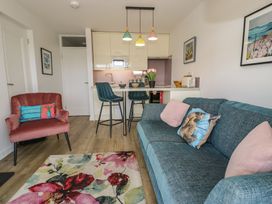 A living room with a couch and kitchen area at Lan y Mor in Porthmadog