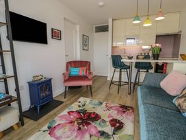 A living room with an armchair and kitchen counter at Lan y Mor in Porthmadog