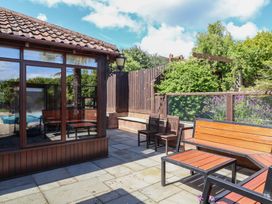 An outdoor patio area with seating and a pool at The Old Byres in Washford near Watchet