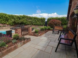 A garden with benches and paved patio at The Old Byres in Washford near Watchet