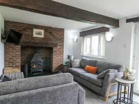 A living room with a fireplace and sofas at Rhosydd Cottage in Benllech