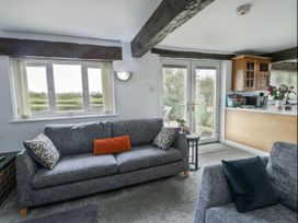 A living room with a sofa and kitchen counter at Rhosydd Cottage in Benllech