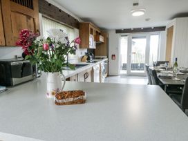 A kitchen with flowers on the counter and a dining table at Rhosydd Cottage in Benllech
