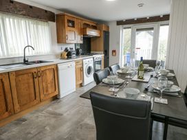 A kitchen with dining table and appliances at Rhosydd Cottage in Benllech