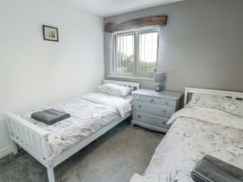 A bedroom with two beds and a dresser at Rhosydd Cottage in Benllech