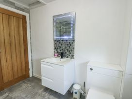 A bathroom with a vanity unit and mirror at Rhosydd Cottage in Benllech