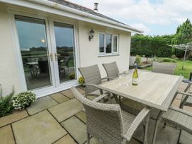A patio area with a table and chairs at Rhosydd Cottage in Benllech