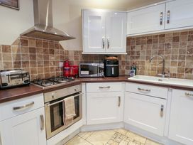 A kitchen with a stove, oven, toaster, and microwave at Y Enciliad in Rhosneigr