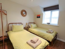 A bedroom with two beds and a window at Y Enciliad in Rhosneigr