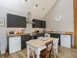 A kitchen with black cabinets wooden countertops a dining table with chairs and appliances at The Barn at Daubeneys in Colerne